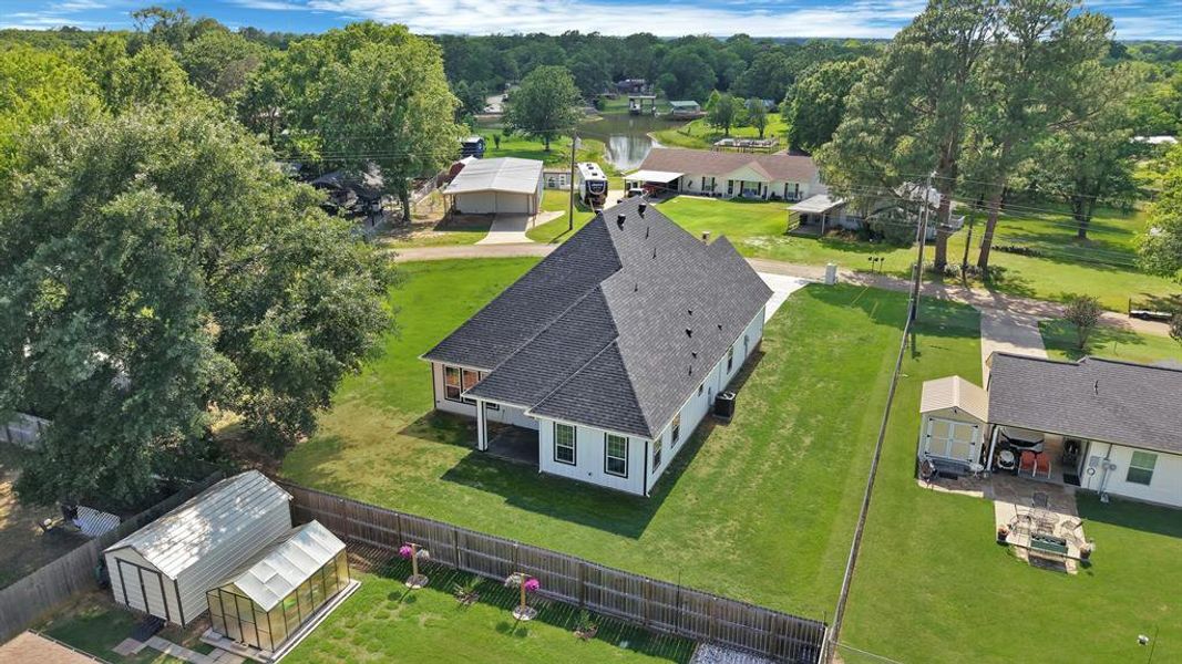 Expansive property featuring a modern residence with a dark shingle roof, white siding, and covered patio space