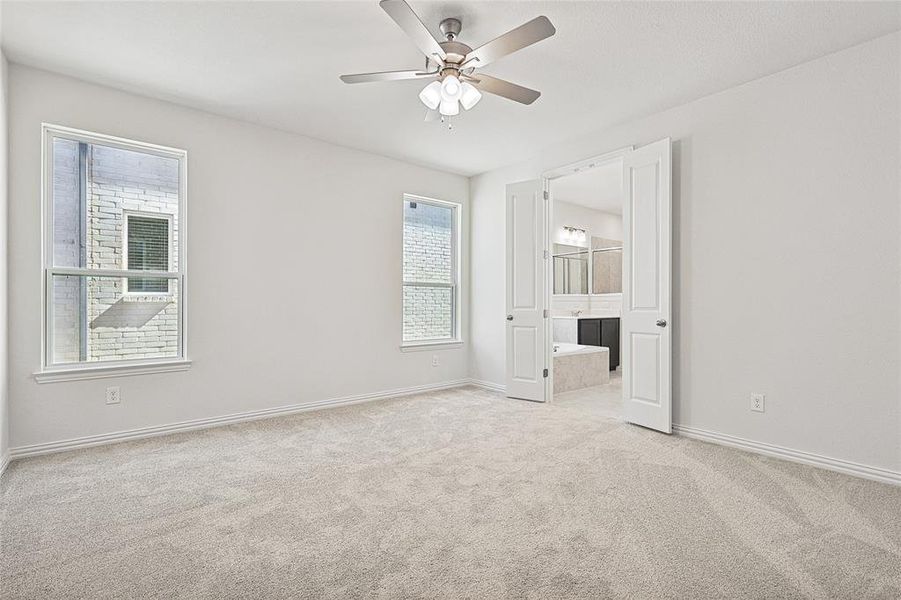 Unfurnished bedroom with ensuite bath, light colored carpet, and ceiling fan