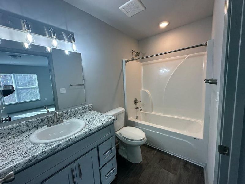 Full bathroom with toilet, bathtub / shower combination, wood-type flooring, and vanity