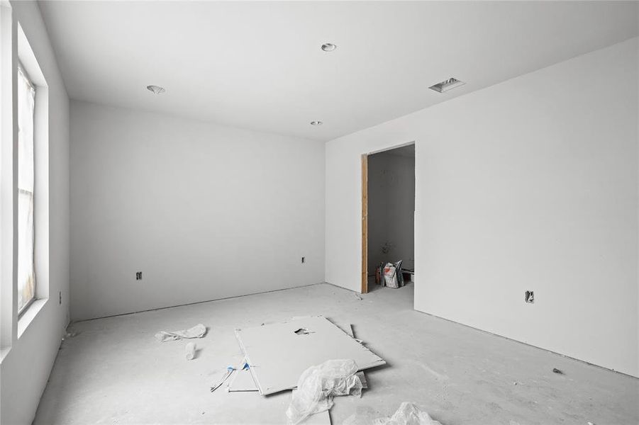 Spacious room featuring white painted walls, recessed lighting, and a large window providing natural light