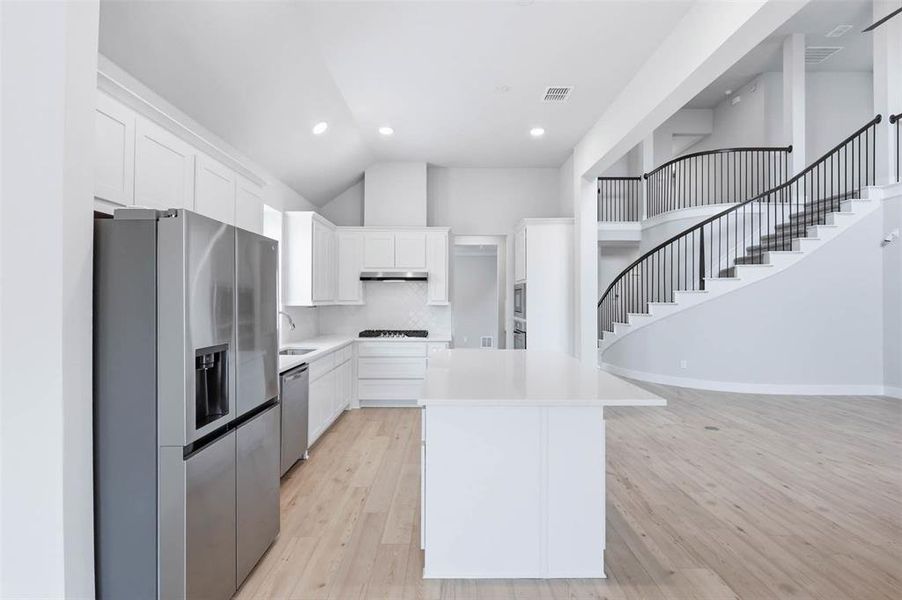 Open kitchen and dining area with modern finishes and easy access to the staircase and main living space.