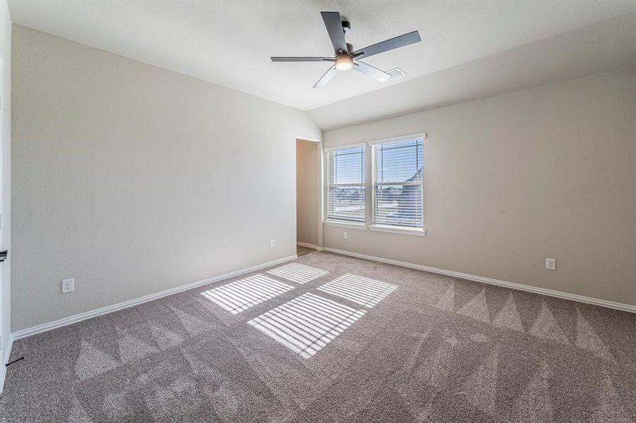 Bright interior room featuring a neutral color palette, twin windows with blinds, a ceiling fan with integrated lighting, and textured carpet flooring