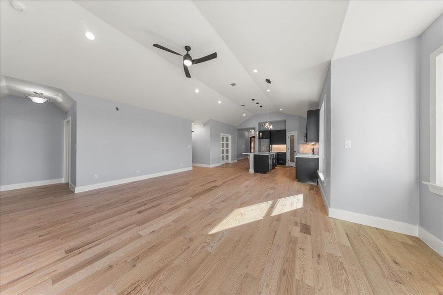 Unfurnished living room featuring vaulted ceiling, a ceiling fan, recessed lighting, and light wood-style flooring Unfurnished living room featuring vaulted ceiling, a ceiling fan, recessed lighting, and light wood-style flooring