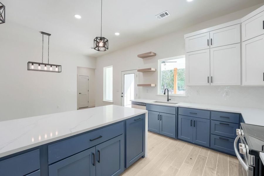 A well-appointed kitchen showcasing contemporary blue and white cabinetry with pristine countertops.