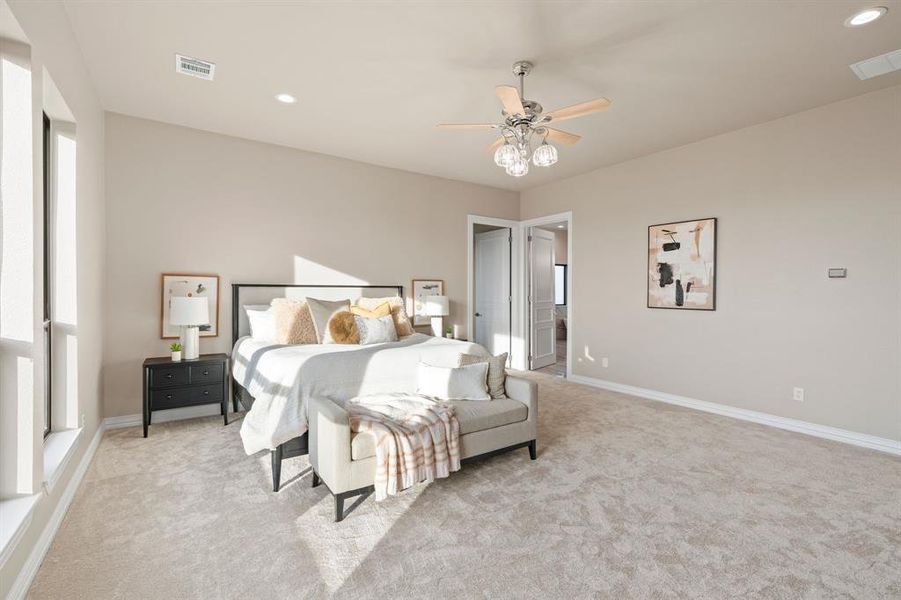 Bedroom with ceiling fan, light colored carpet, and ensuite bath