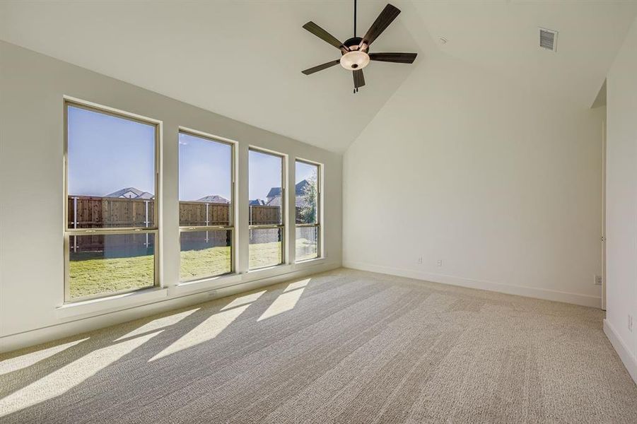 Spare room with high vaulted ceiling, light colored carpet, and a ceiling fan