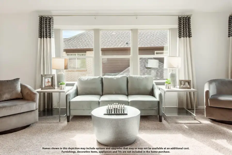 Living room with gray sofa, round coffee table, and large windows with neutral curtains