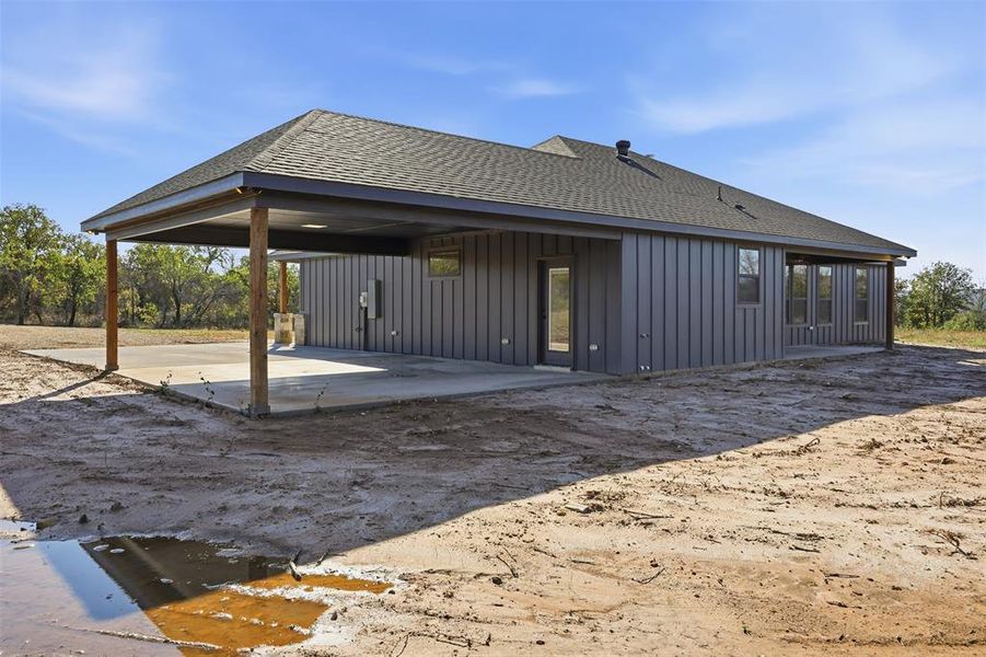 Rear view of house with roof with shingles, board and batten siding, and a patio area Rear view of house with roof with shingles, board and batten siding, and a patio area