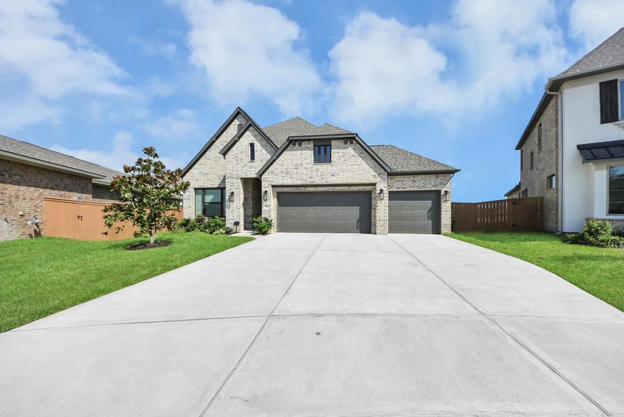 Stunning brick home with a spacious three-car garage, set on a beautifully manicured lawn.