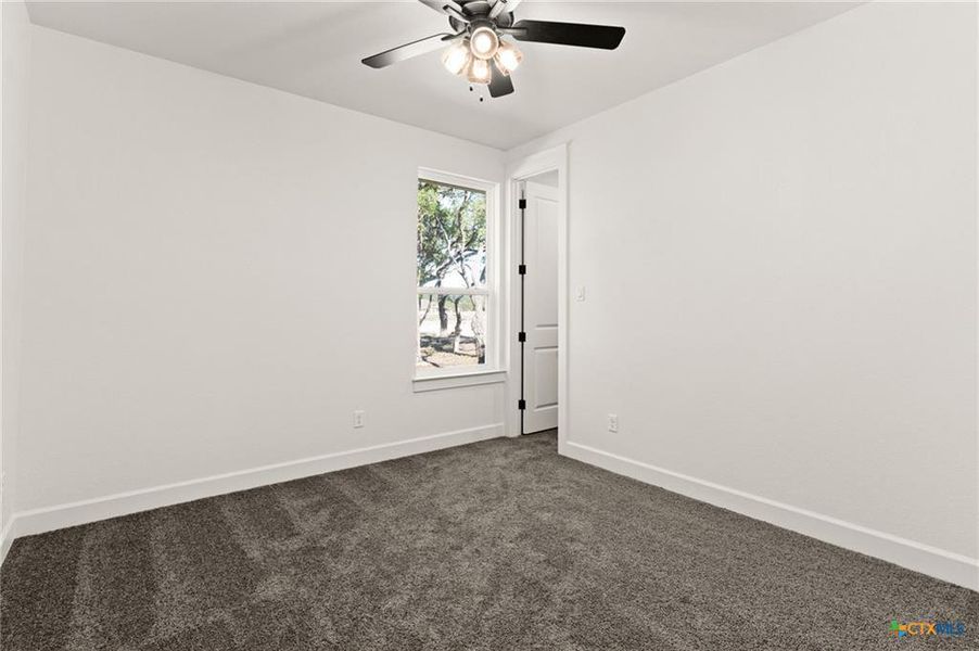Empty room with dark carpet and a ceiling fan