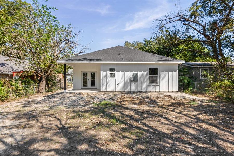 Rear view of property with french doors, a patio, and a shingled roof