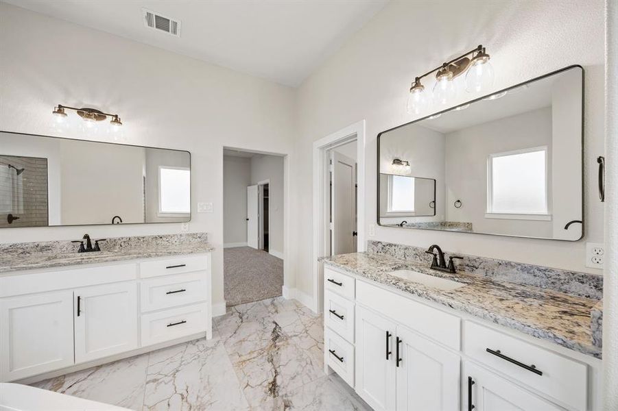 Full bath featuring light marble finish flooring, two vanities, and a shower with door Full bath featuring light marble finish flooring, two vanities, and a shower with door