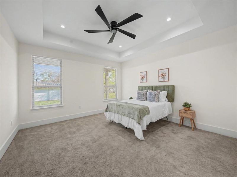 Bedroom featuring light colored carpet, ceiling fan, a tray ceiling, and recessed lighting