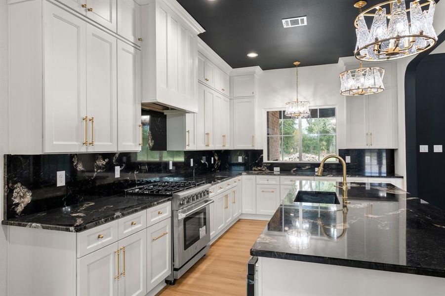 Kitchen featuring dark stone counters, pendant lighting, arched walkways, stainless steel gas stove, and tasteful backsplash