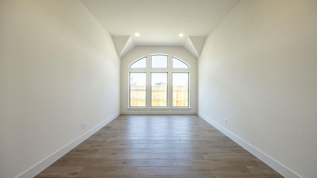 Spare room featuring light wood-style flooring and lofted ceiling