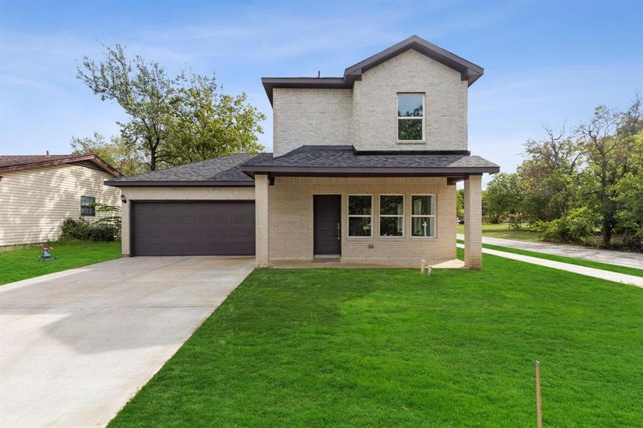 View of front facade featuring a garage and a front lawn