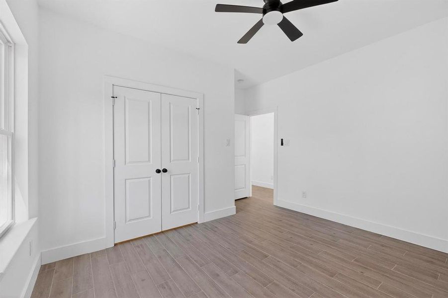 Unfurnished bedroom featuring wood finish floors, a closet, and ceiling fan