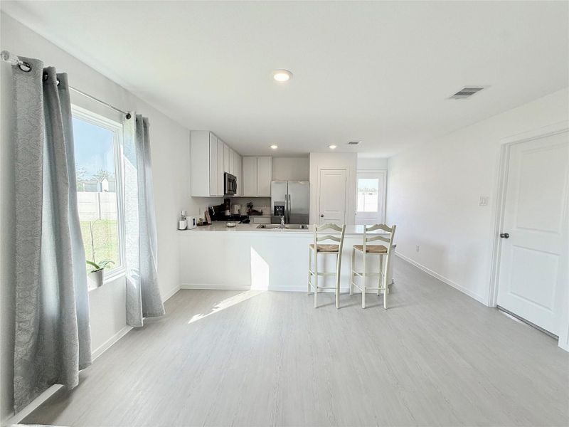 Modern light gray wood-look laminate flooring adds style and warmth perfectly complementing the bright open dining area and kitchen. Modern light gray wood-look laminate flooring adds style and warmth perfectly complementing the bright open dining area and kitchen.