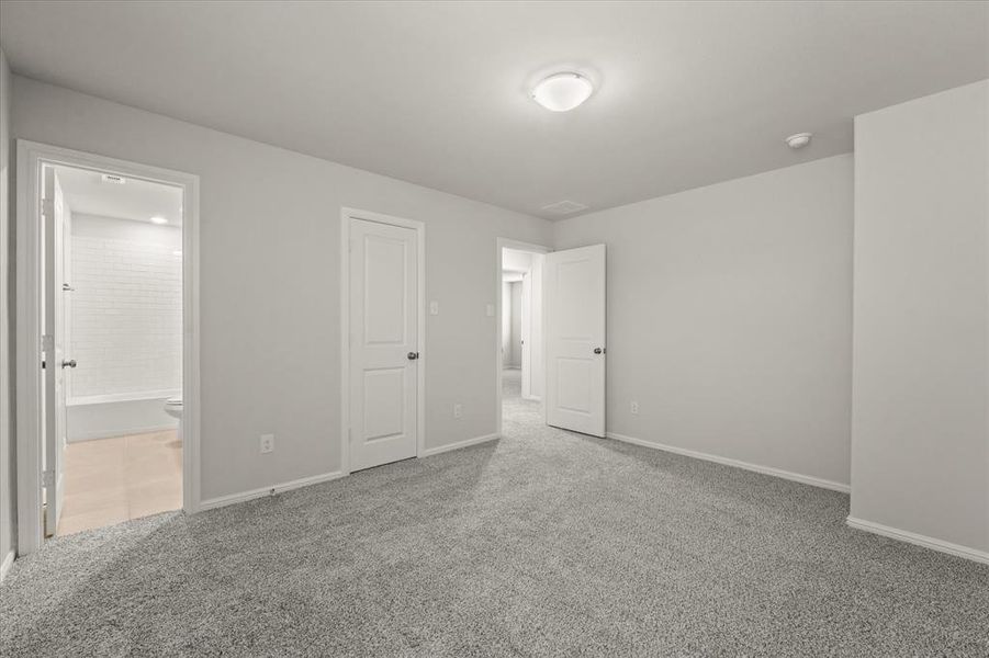 Unfurnished bedroom featuring ensuite bathroom, a closet, and carpet flooring