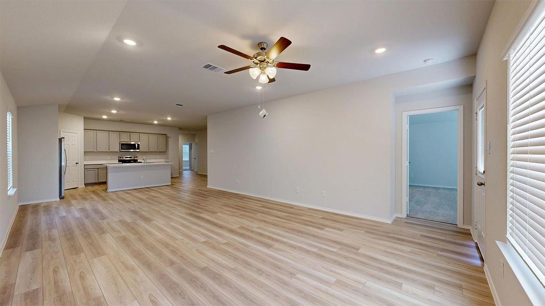 An inviting open-concept living space features light wood flooring and a contemporary kitchen.