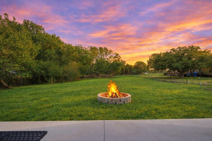 The property features an extensive lawn with a fire pit, surrounded by mature trees