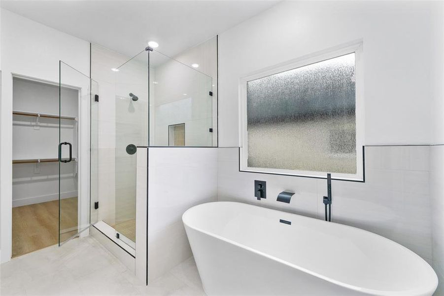 Freestanding soaking tub with matte black fixtures, framed by a privacy window Freestanding soaking tub with matte black fixtures, framed by a privacy window
