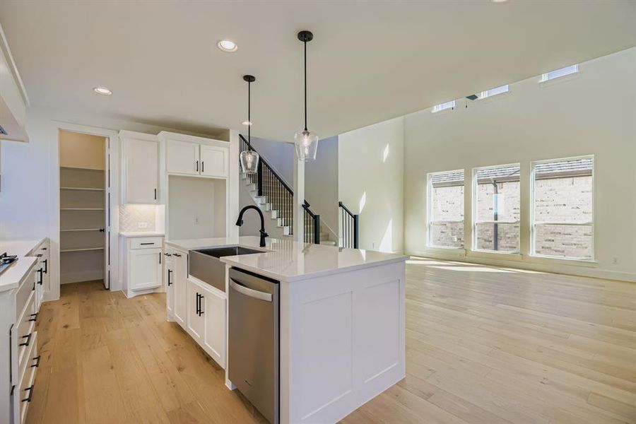 Kitchen with recessed lighting, a center island with sink, pendant lighting, stainless steel dishwasher, and light wood-type flooring Kitchen with recessed lighting, a center island with sink, pendant lighting, stainless steel dishwasher, and light wood-type flooring