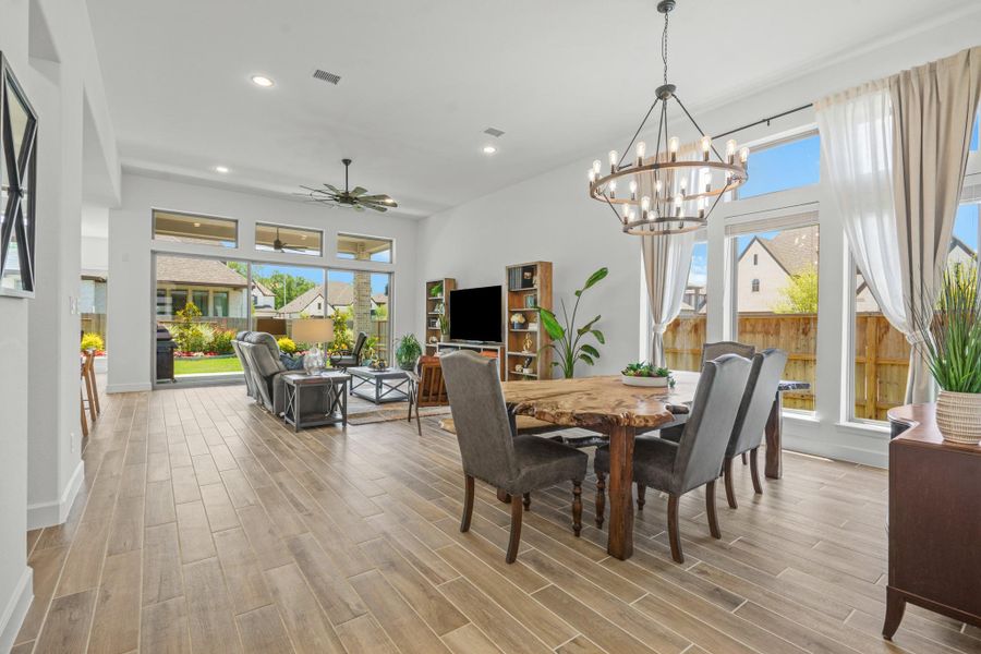 This spacious, open-concept living and dining area features elegant wood tile flooring and ample natural light from large windows. It includes a modern multi-Eddison bulb chandelier.  Perfect for entertaining and family gatherings.