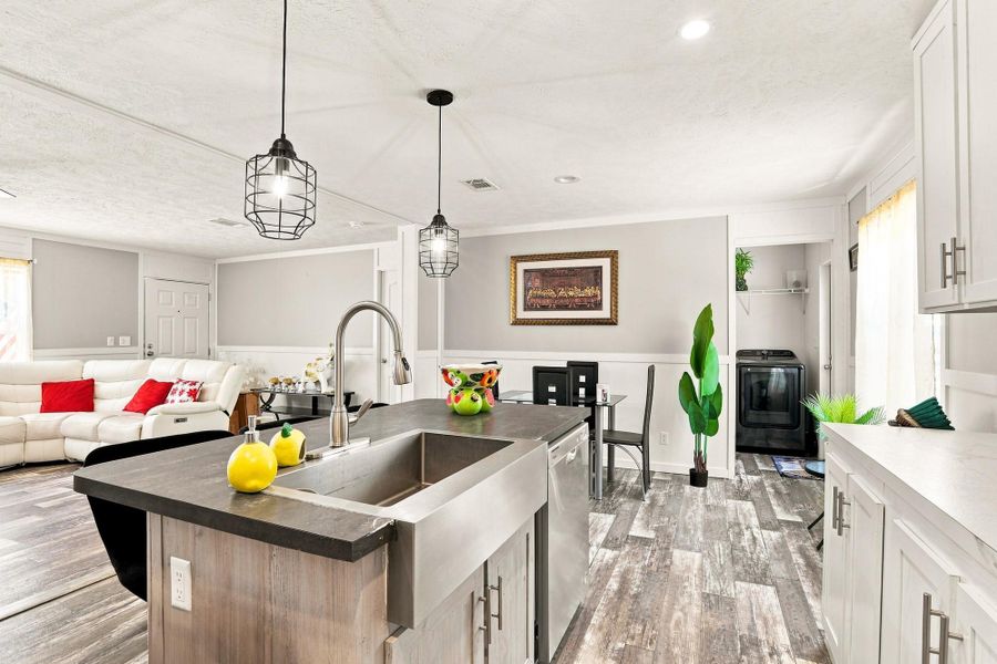 An open kitchen layout transitions smoothly into dining and living spaces over modern plank flooring.