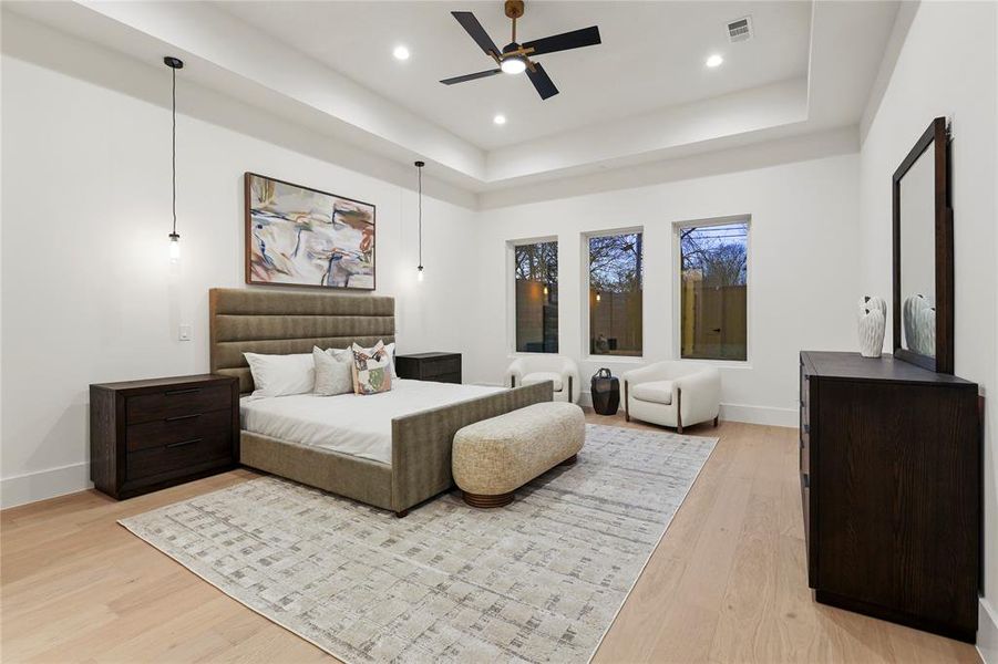 Bedroom featuring light wood-style flooring, a tray ceiling, a ceiling fan, and recessed lighting