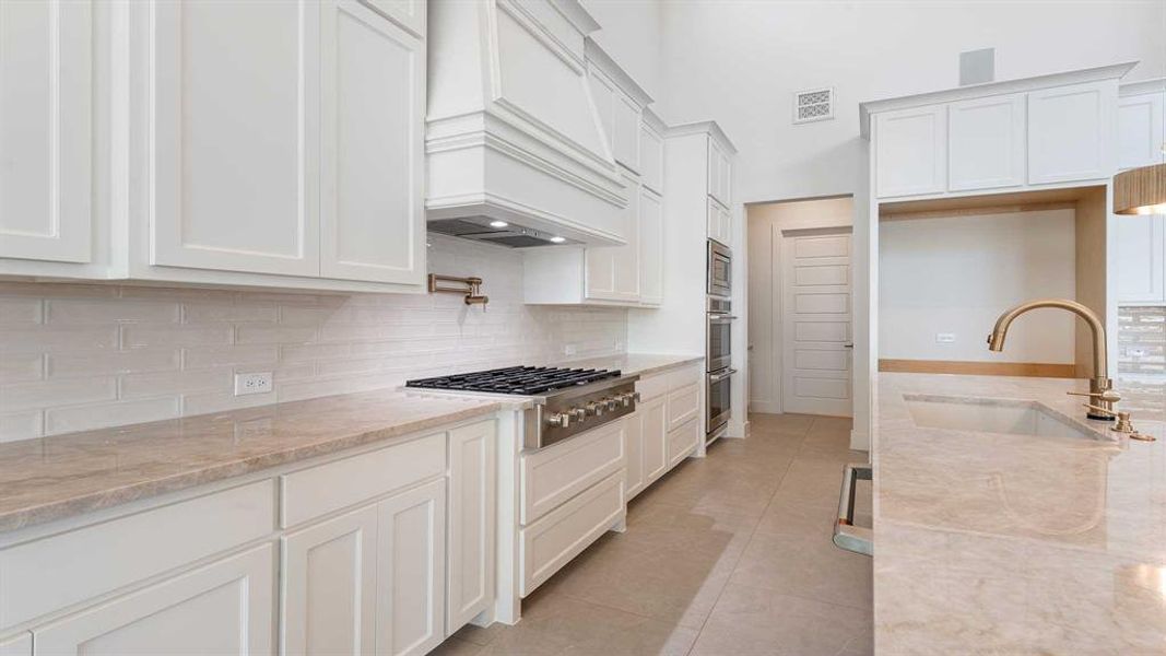 Kitchen with white cabinetry, sink, light tile patterned floors, and appliances with stainless steel finishes