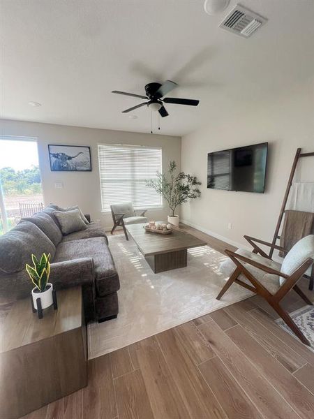 Living room featuring wood tiled floors, plenty of natural light, and ceiling fan