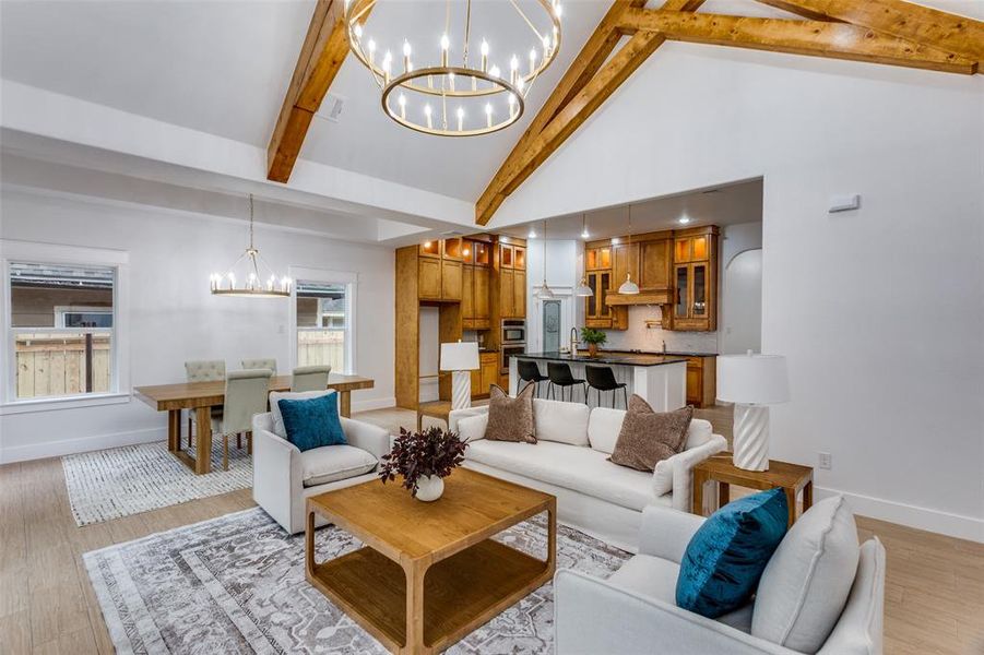 Living room featuring beamed ceiling, a notable chandelier, high vaulted ceiling, and light hardwood / wood-style flooring