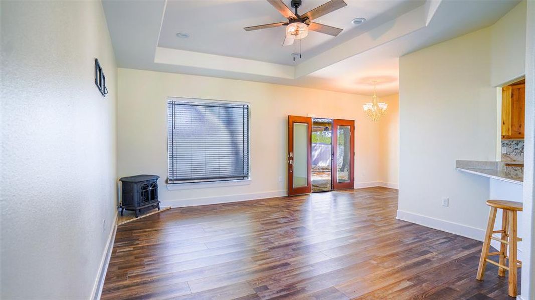 Living room with a ceiling fan, wood-style flooring, hanging lights, and a tray ceiling Living room with a ceiling fan, wood-style flooring, hanging lights, and a tray ceiling