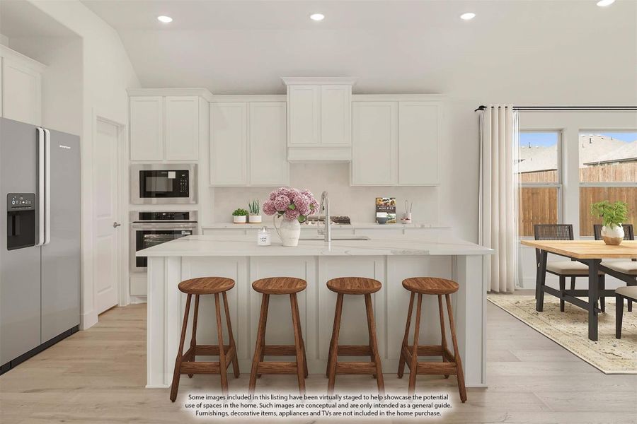 Kitchen with white cabinets, center island with four bar stools, stainless steel appliances, and light wood floors
