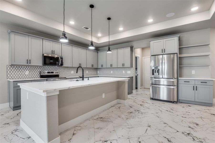 Kitchen with gray cabinetry, open shelves, stainless steel appliances, a raised ceiling, and decorative light fixtures