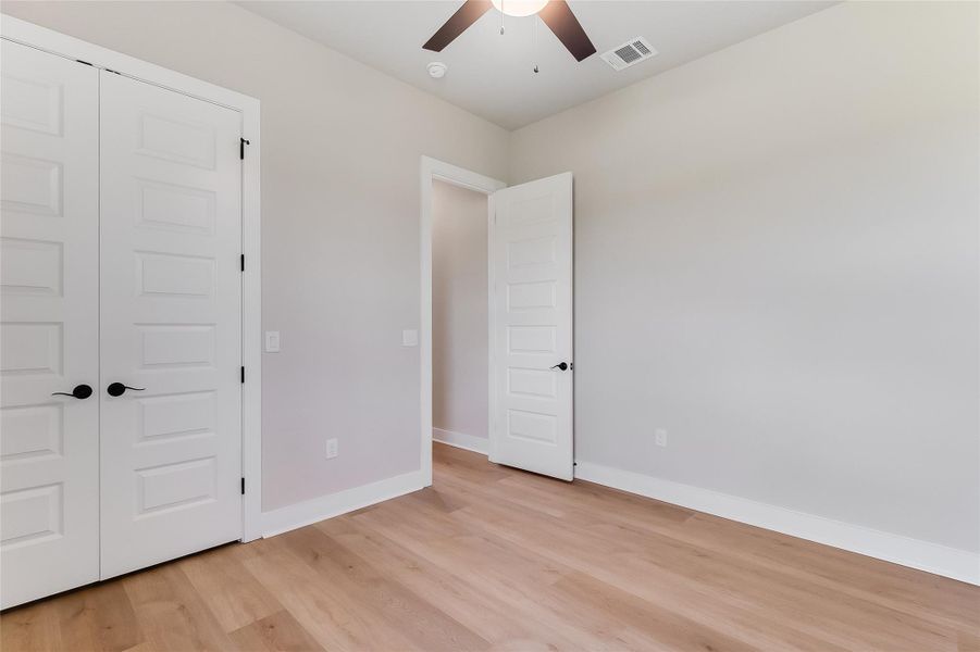 Unfurnished bedroom featuring light wood-style flooring, a ceiling fan, and a closet