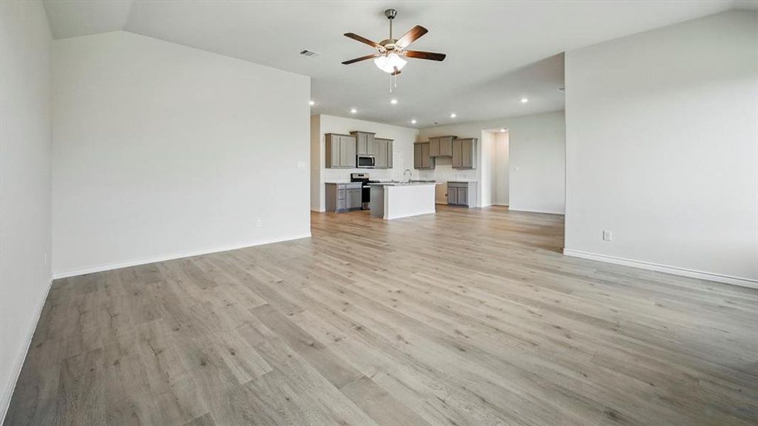 Unfurnished living room with light wood-type flooring, lofted ceiling, ceiling fan, and recessed lighting