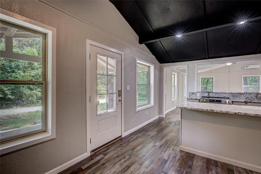 Doorway to outside with vaulted ceiling with beams and dark wood-type flooring