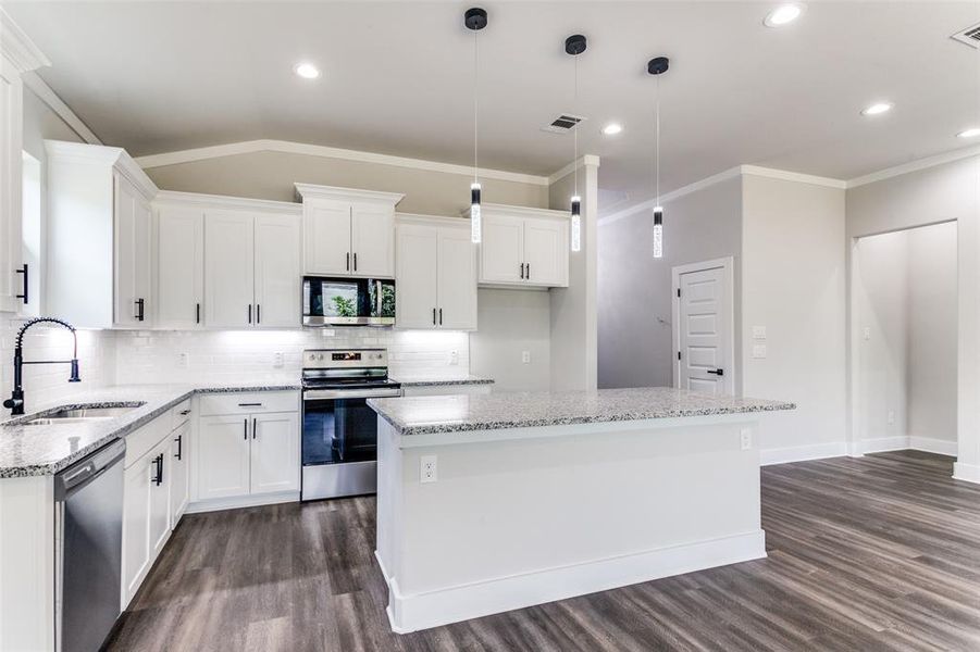 Kitchen with appliances with stainless steel finishes, a center island, and dark wood-type flooring