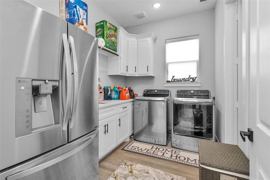 The utility room is accessible from the primary bath and has sink, quartz counter, storage, room for fridge and natural light.