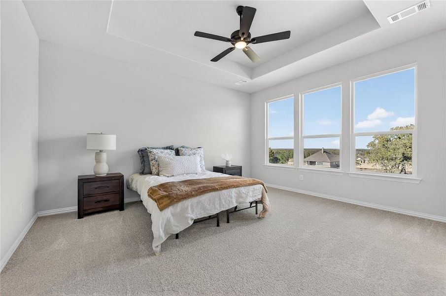 Bedroom featuring a tray ceiling, light carpet, and ceiling fan Bedroom featuring a tray ceiling, light carpet, and ceiling fan