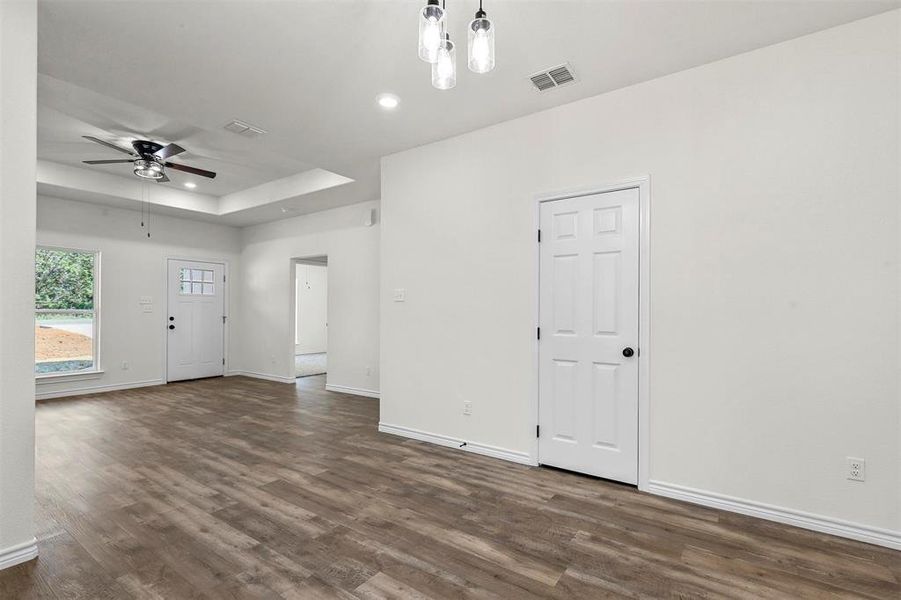 Unfurnished living room with a raised ceiling, ceiling fan, and dark hardwood / wood-style floors