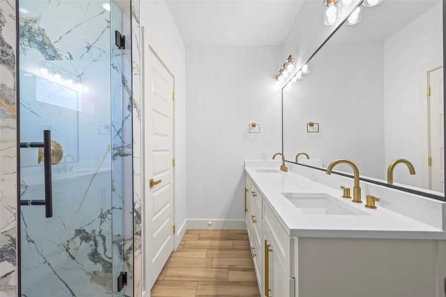 Full bathroom featuring double vanity, a marble finish shower, and light wood-type flooring