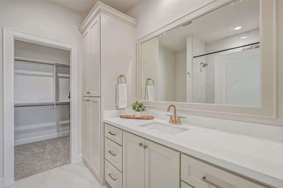 Serving the remaining upstairs bedrooms, this full bath offers a generous vanity with abundant cabinetry, oversized mirror & brushed-gold fixtures, plus a separate tub/shower area finished with marble-look tile.