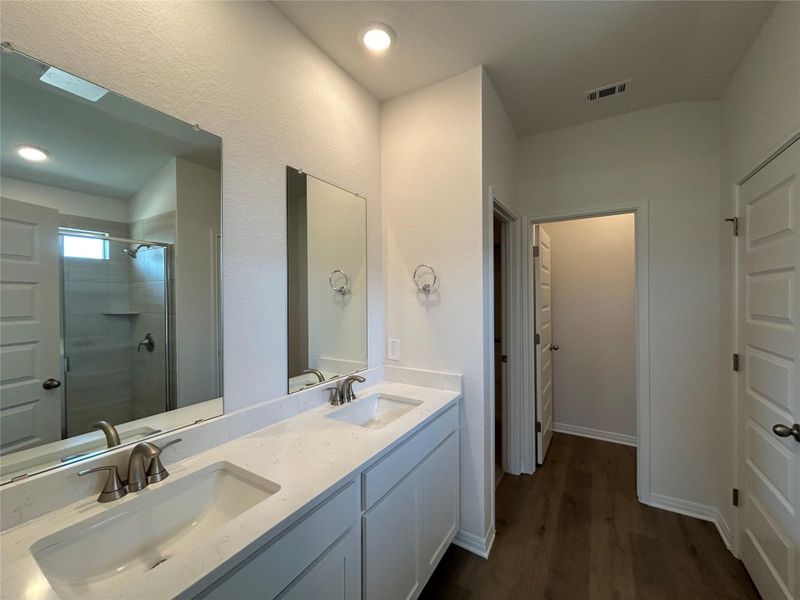 Bathroom featuring a stall shower, double vanity, dark wood finished floors, and recessed lighting Bathroom featuring a stall shower, double vanity, dark wood finished floors, and recessed lighting