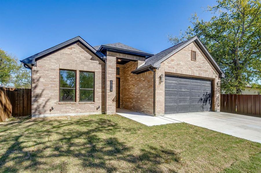 View of front of home featuring driveway, brick siding, and a garage