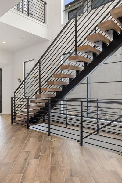 Open-tread staircase with metal railings and wood-finish flooring