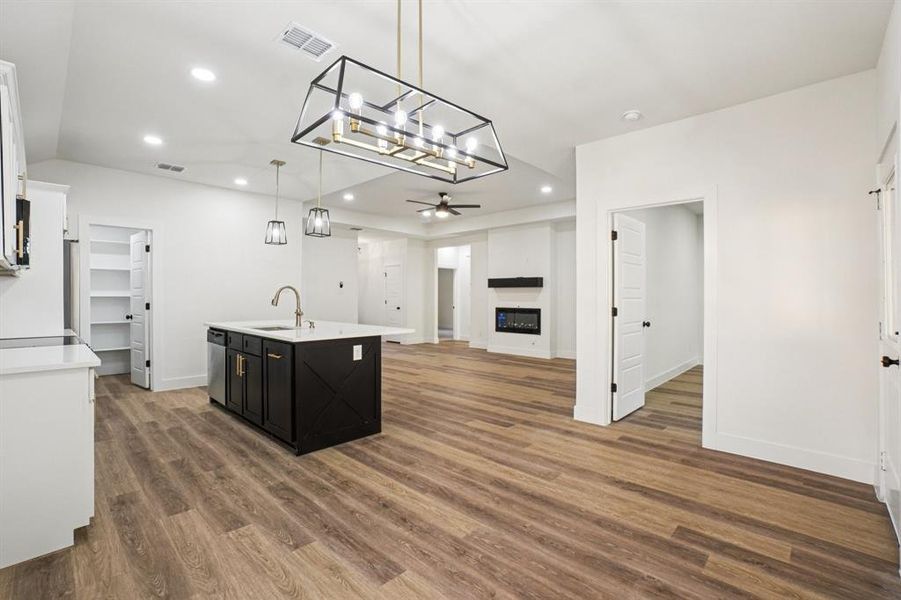 Kitchen with a glass covered fireplace, open floor plan, recessed lighting, pendant lighting, and a center island with sink Kitchen with a glass covered fireplace, open floor plan, recessed lighting, pendant lighting, and a center island with sink