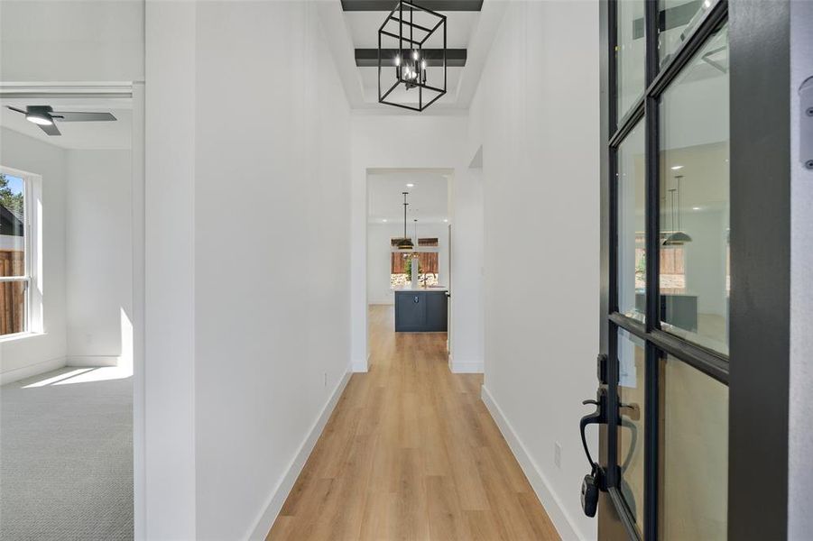 Hallway with wood-type flooring, a high ceiling, and a chandelier